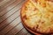 Top view on tasty traditional megrelian khachapuri - pie with melted salt cheese suluguni and egg yolk on wooden tray