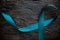 Top view of teal ribbon on dark background with copy space. Cervical and ovarian cancer, sexual assault, pcos, ptsd, anxiety disor