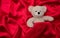 Top view of teddy bear on red silk background