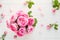 Top view tender pink tea roses bouquet on the rustic white wooden table with petals. Floral background. Greeting postcard mock up.