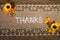 Top view of the Thanks word and artificial flowers on embroidered linen fabric