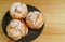 Top View of Three Choux a la Creme Pastries or French Cream Puffs on a Black Plate Served on Wooden Table