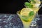 Top view of three glasses of mojito, with selective focus, with lime and mint slices on blue marble and black background horizonta