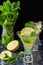 Top view of three glasses of mojito, with selective focus, with lime wedges and sprig of mint on blue marble and black background