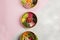 Top view of three plates full of diet dishes on a grey and pink background- vegan food concept