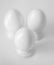 Top view of three white decorative ceramic eggs on stands or in egg-cups on white blurred background. Easter religious Christian s