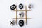 Top view of tic tac toe game with grid made of pencils, and pebbles marked with crosses and naughts