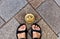 Top view of tired tourist legs in sandals and brass crown marker in cobblestone streets