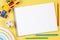 Top view to blank open sketchbook notebook with colored pencils and educational wooden kid toys and on yellow background