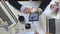 Top view to hands of business people working efficiently using laptops and graphs. Group of young workers sitting at