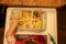 Top view, toddler sits in front of a children`s plate full of delicious mouth-watering food and cuts the food with a