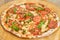 Top view tomato pizza with greens on wooden board.