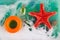 Top view on toy ocean in aquarium. Top view on blue watr with white foam, red starfish, stone, small glass bottle and round orange