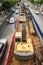 Top view, a tracked excavator on a construction site at traffic island, vehicle moving on an asphalt road