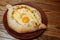 Top view on traditional Adjarian Khachapuri - open baked pie with melted salt cheese suluguni and egg yolk on wooden