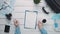 Top view traveler`s hands holding pen and cup of coffee and clipboard with paper at white wooden desk