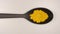 TOP VIEW: Turmeric powder in a plastic spoon on a table