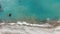 Top view of turquoise Mediterranean Sea waters rolling on pebbles. Aerial view of transparent foamy waves splashing on