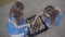 Top view of two brunette caucasian twin sisters playing chess indoors. Little girls in elegant blue dresses resting