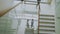 Top view of two businessmen meet at staircase in modern office center and talking while female colleagues walking stairs