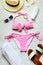 Top view of two pieces pink swimming suit and beach accessoties over wooden background.