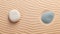 top view of two stones with blue and grey spots on beige sand