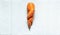 Top view of ugly deformed twisted carrot on a white paper background, ugly organic food, zero waste concept