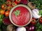 Top view of Ukrainian cream borscht in a bowl with pea microgreen. The ingredients are laid out around the bowl: beets, cherry