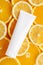 Top view of unbranded bottle for cosmetics product. Plastic flacon for cream, body lotion or toiletry. Juicy slices of orange and