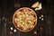 Top view of uncut Italian pizza with variety of cheese, cherry tomatoes, champignons, quail eggs and sea salt on wooden backgrou