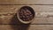 TOP VIEW: Unpeeled pine nuts fill wooden cup on a wooden table