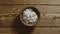 TOP VIEW: Unpeeled pumpkin seeds fill wooden cup on a wooden table