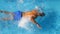 Top view of unrecognizable sporty man jumping in clear blue water of pool. Young muscular guy floating across the basin