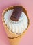 Top view vanilla ice cream cone scoop with chocolate chip cookies on pink background, vertical shot