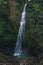 Top view from the vantage point of a huge waterfall with cold water falling from the lush green mountain with some tourists at the