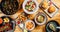 Top view of a variety of seafood, salads, and fried potatoes with sauces on trays on the table