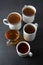 Top view of various cups, mugs with hot tea drink on dark background, copy space. Tea time or tea brake. Autumn beverage. Toned