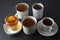 Top view of various cups, mugs with hot tea drink on dark background, copy space. Tea time or tea brake. Autumn beverage. Toned