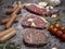 Top view of various cuts of raw meat steak with herbs on grey concrete background. food preparation concept.