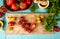 top view of vegetables as tomato coriander on cutting board with garlic crusher black pepper on blue background