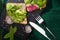 Top view of vegetarian toasts with fresh vegetables on cloth and stone board with fork and knife.