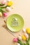 Top view vertical photo of green plate with inscription happy easter cutlery easter eggs yellow and pink tulips