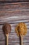 Top view vertical shot of two wooden spoons overflowing with brown lentils and corn kernels