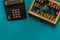 Top view of vintage abacus and modern calculator on a green background, the concept of finance and mathematical calculations