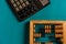 Top view of vintage abacus and modern calculator on a green background, the concept of finance and mathematical calculations