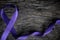 Top view of violet ribbon on dark wood background with copy space. Hodgkin lymphoma cancer awareness concept.