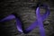Top view of violet ribbon on dark wood background with copy space. Hodgkin lymphoma cancer awareness concept.