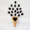 Top view waffle sweet ice cream cone with blackberries on a white wooden table. Flat lay, overhead