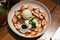 Top view of waffle topping with a scoop of vanilla ice cream, whip cream, sliced strawberry, mint leaves and chocolate sauce.