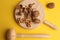 Top view of walnuts on a wooden cutting board with a mallet on a yellow background